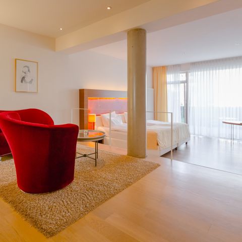 Nahaufnahme der roten Sitzecke in der Superior Suite mit Doppelbett und Terrassentür