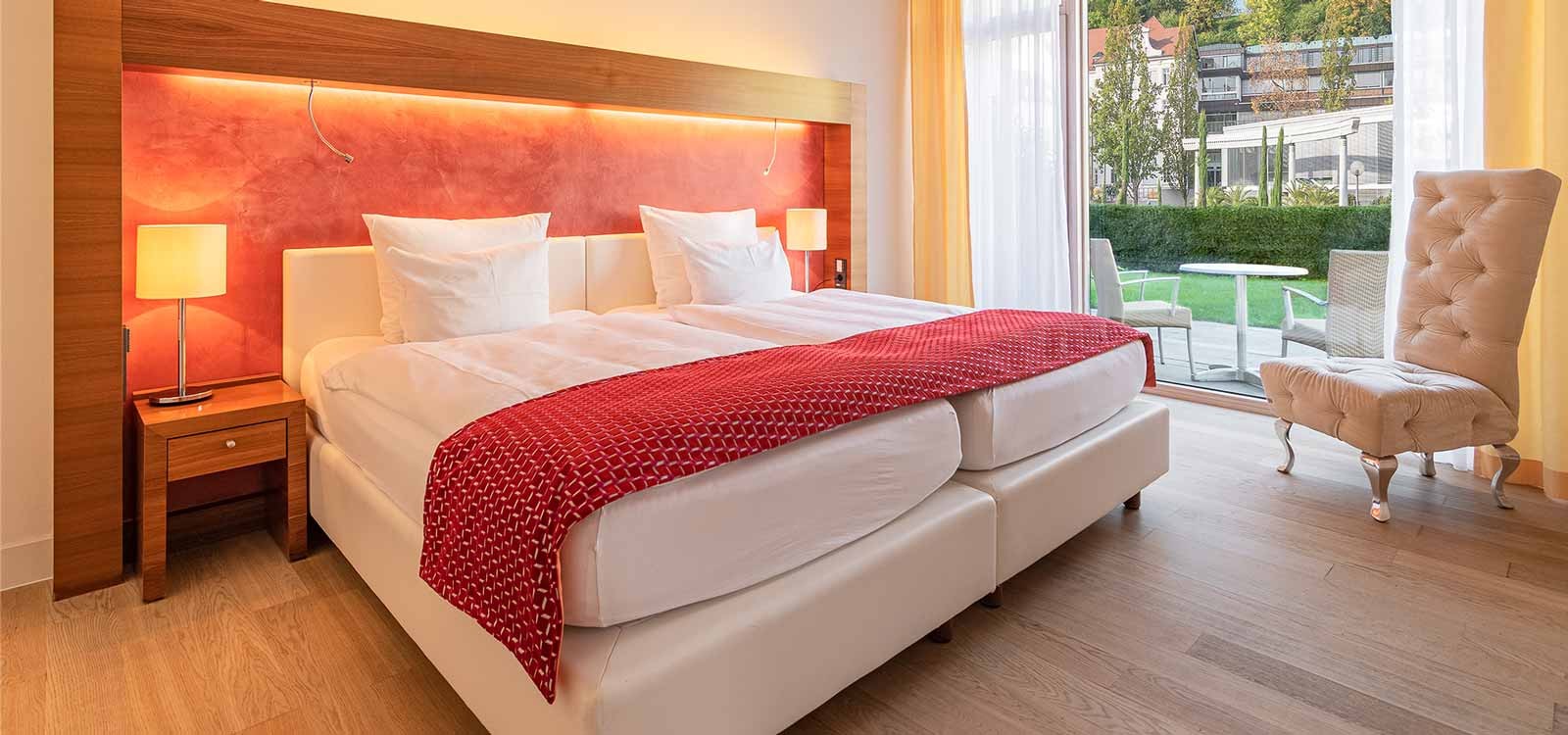Aufnahme eines großen gemütlichen Bettes einer Suite mit Gartenzugang im 4-Sterne Hotel in Baden-Baden
