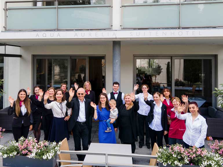 Das Team des 4-Sterne Hotels in Baden-Baden steht auf der Terrasse und winkt